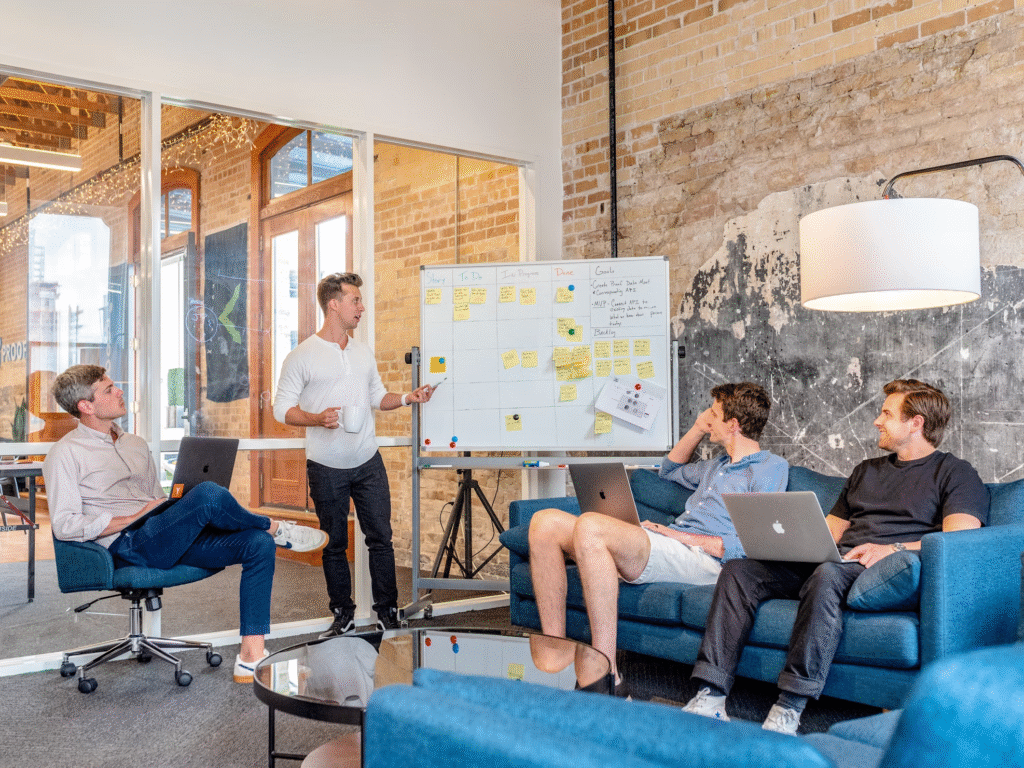 An Influencer’s Guide to How to Pitch Brand Collaborations 1 Group of men around a white board figuring out how to pitch brand collaborations.